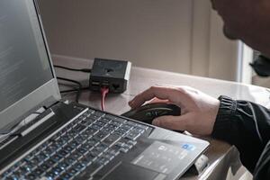 proche en haut de homme main en utilisant sans fil Souris et portable ordinateur avec bleu rétro-éclairé clavier photo