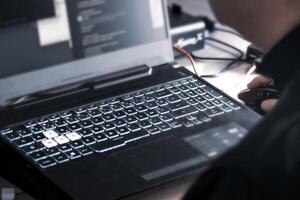 proche en haut de homme main en utilisant sans fil Souris et portable ordinateur avec bleu rétro-éclairé clavier photo