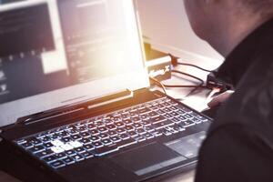 proche en haut de homme main en utilisant sans fil Souris et portable ordinateur avec bleu rétro-éclairé clavier photo