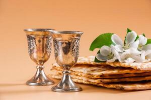 content pâque. traditionnel juif vacances. argent du vin tasses, printemps fleurs et azyme pain photo