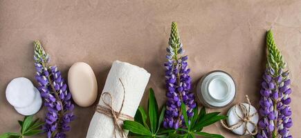 Naturel biologique produits de beauté et lupin fleurs sur artisanat papier Contexte. hydratant crème, savon et serviette. corps se soucier concept. spa et beauté traitements, relaxation. copie espace, bannière format. photo