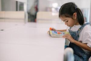 une Jeune fille est séance à une table en train de lire une livre photo