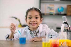 asiatique enfant fille apprentissage science chimie avec tester tube fabrication expérience à école laboratoire. éducation, science, chimie, et enfants concepts. de bonne heure développement de les enfants. photo