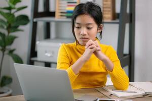 une Jeune fille est séance à une bureau avec une portable ouvert dans de face de sa photo