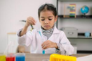 asiatique enfant fille apprentissage science chimie avec tester tube fabrication expérience à école laboratoire. éducation, science, chimie, et enfants concepts. de bonne heure développement de les enfants. photo