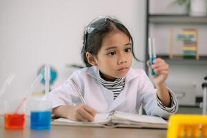 asiatique enfant fille apprentissage science chimie avec tester tube fabrication expérience à école laboratoire. éducation, science, chimie, et enfants concepts. de bonne heure développement de les enfants. photo