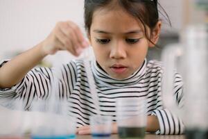 asiatique enfant fille apprentissage science chimie avec tester tube fabrication expérience à école laboratoire. éducation, science, chimie, et enfants concepts. de bonne heure développement de les enfants. photo