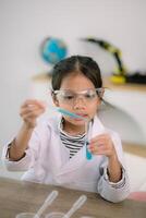 peu mignonne fille avec une microscope en portant une laboratoire bouteille avec l'eau expérience étude scientifiques à école. éducation science concept. photo