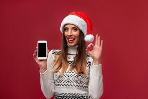 proche en haut portrait magnifique caucasien femme dans rouge Père Noël chapeau sur rouge studio Contexte. Noël et Nouveau année vacances concept. photo