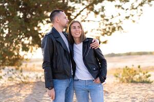 content et mignonne adorable adulte couple de millénaire les hipsters, homme avec femme petite amie marche, avoir amusement jouer, rire sourire et sauter sur le coucher du soleil à désert photo