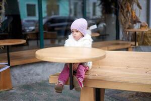 malheureux peu fille séance Extérieur café à table l'automne saison caucasien femelle enfant perdu dans ville séance triste photo