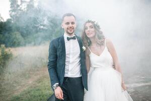 une homme dans une costume étreindre le sien petite amie en plein air, le la mariée et jeune marié sur le sien mariage journée photo