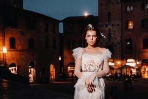 une la mariée dans une blanc robe dans le vieux ville de san gimignano.a fille des promenades autour le ville dans italie.toscane. photo