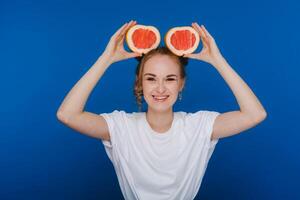 surpris, le en riant fille détient le pamplemousse comme oreilles. végétalien mode de vie. souriant femme , en mangeant concept.régime biologique , poids perte et en bonne santé aliments. smoothies et Frais jus. photo