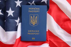 ukrainien biométrique passeport sur plié agitant drapeau de uni États de Amérique photo