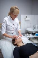 beuticienne médecin essuyage les patients visage avec coton tampons. portrait de femme sur nettoyage visage procédure par femme cosmétologue dans beauté clinique. beauté industrie concept. photo