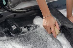 laver le tapis de voiture.détailler à l'intérieur de la voiture moderne.nettoyer en utilisant une brosse et une solution de nettoyage sur le tapis de voiture. photo