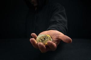 un bitcoin doré dans la main d'un homme mystérieux. photo