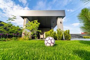 Balle sur vert pelouse. moderne obsolète maison Contexte. bleu ciel au-dessus de. personne dans le cour. Football Balle sur le pelouse. moderne architecture. photo