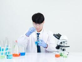 portrait asiatique homme étudiant scientifique médecin dans chemise robe un la personne wok emploi plante à la recherche main en portant contrôle microscope sur blanc table voir le résultats de scientifique expériences à l'intérieur laboratoire photo