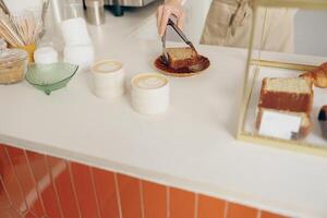 le serveuse main met le pièce de petit gâteau sur le table à une café permanent derrière bar compteur photo