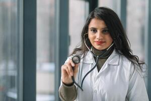 Jeune Indien médical étudiant à le clinique dans entraine toi en utilisant une stétoscope dans de face de caméra photo