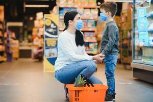 mère et fils sont achats à le épicerie magasin. elles ou ils porter masques pendant quarantaine. coronavirus pandémie .coved-19 éclair. le épidémie de le virus. photo