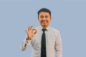 adulte asiatique homme souriant amical et donnant D'accord signe avec les doigts photo