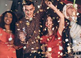 bonne humeur. l'air dans les confettis. quatre bons amis dans les bons vêtements sont à la fête du nouvel an photo