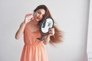 vue de face. belle jeune femme tenant un miroir et regardant l'outil sourcils photo