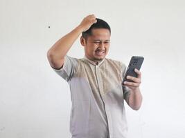 adulte asiatique homme montrant confus expression lorsque à la recherche à le sien téléphone photo