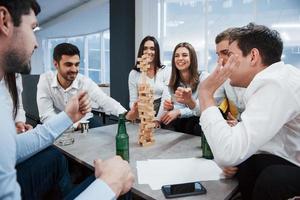 faites attention s'il vous plait. célébrant l'accord réussi. jeunes employés de bureau assis près de la table avec de l'alcool photo