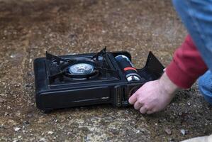 actif mode de vie. une homme main se tourne sur une portable gaz poêle. un alternative la source pour cuisine à Accueil pendant une Puissance panne. photo