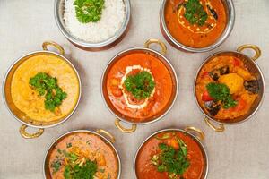 assorti Indien nourriture plaine riz, poulet beurre Masala, du boeuf Handi, champignon jalfrezi, poulet Korma, poulet curry, poulet le Chili, du boeuf vindaloo servi dans une plat isolé sur table Haut vue photo