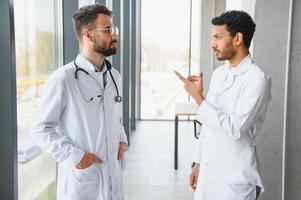 un Indien médecin et une européen médecin supporter ensemble dans une hôpital hall photo