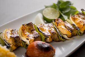 Bakhteari tikka kabab avec citron vert et salade servi dans plat isolé sur gris Contexte Haut vue de arabe nourriture photo