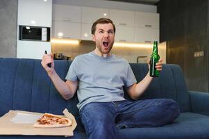 en train de regarder le Football Jeu en mangeant pizza, boire bière. photo