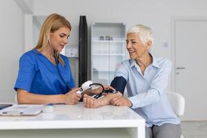 mesure du sang pression. Sénior femme avoir une visite avec femelle médecin dans moderne clinique. mesure du sang pression. pression jauge. hypertension et haute cœur taux photo