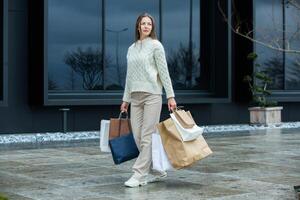 blanc européen Dame vient en dehors de le achats centre avec plein Sacs. magnifique femme en portant achats Sacs. photo