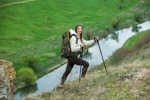 Jeune femme avec sac à dos randonnée dans le montagnes. randonnée concept. trekking falaises. voyage, voyageur. photo