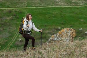 Jeune femme avec sac à dos randonnée dans le montagnes. randonnée concept. trekking falaises. voyage, voyageur. photo