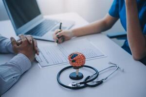 médecin expliquant cerveau les fonctions à patient sur modèle dans bureau. photo