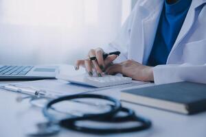 médecin et patient séance à le bureau dans clinique bureau. le concentrer est sur femelle médecin mains remplissage en haut le des médicaments histoire record former, proche en haut. médicament concept photo