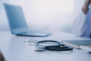 médecin et patient séance à le bureau dans clinique bureau. le concentrer est sur femelle médecin mains remplissage en haut le des médicaments histoire record former, proche en haut. médicament concept photo