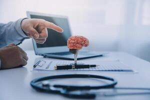 médecin expliquant cerveau les fonctions à patient sur modèle dans bureau. photo