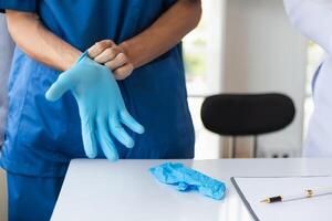 médecin est portant bleu caoutchouc gants prévenir direct contact avec patient car virus mai être tracé à patient corps et médical caoutchouc gants aussi Aidez-moi prévenir virus de étant transmis à patient photo