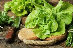 brut vert biologique beurre salade prêt à hacher sur Coupe planche avec couteau photo