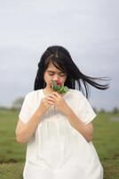 portrait de une jolie Jeune femme habillé dans blanc robe en portant Rose fleurs photo