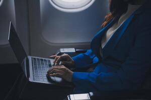 en utilisant mobile et ordinateur portable, réfléchi asiatique gens femelle la personne à bord, avion fenêtre, à la perfection Capturer le anticipation et excitation de vacances Voyage. Chinois, Japonais personnes. photo