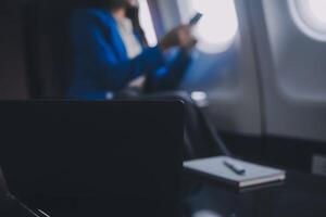 en utilisant mobile et ordinateur portable, réfléchi asiatique gens femelle la personne à bord, avion fenêtre, à la perfection Capturer le anticipation et excitation de vacances Voyage. Chinois, Japonais personnes. photo